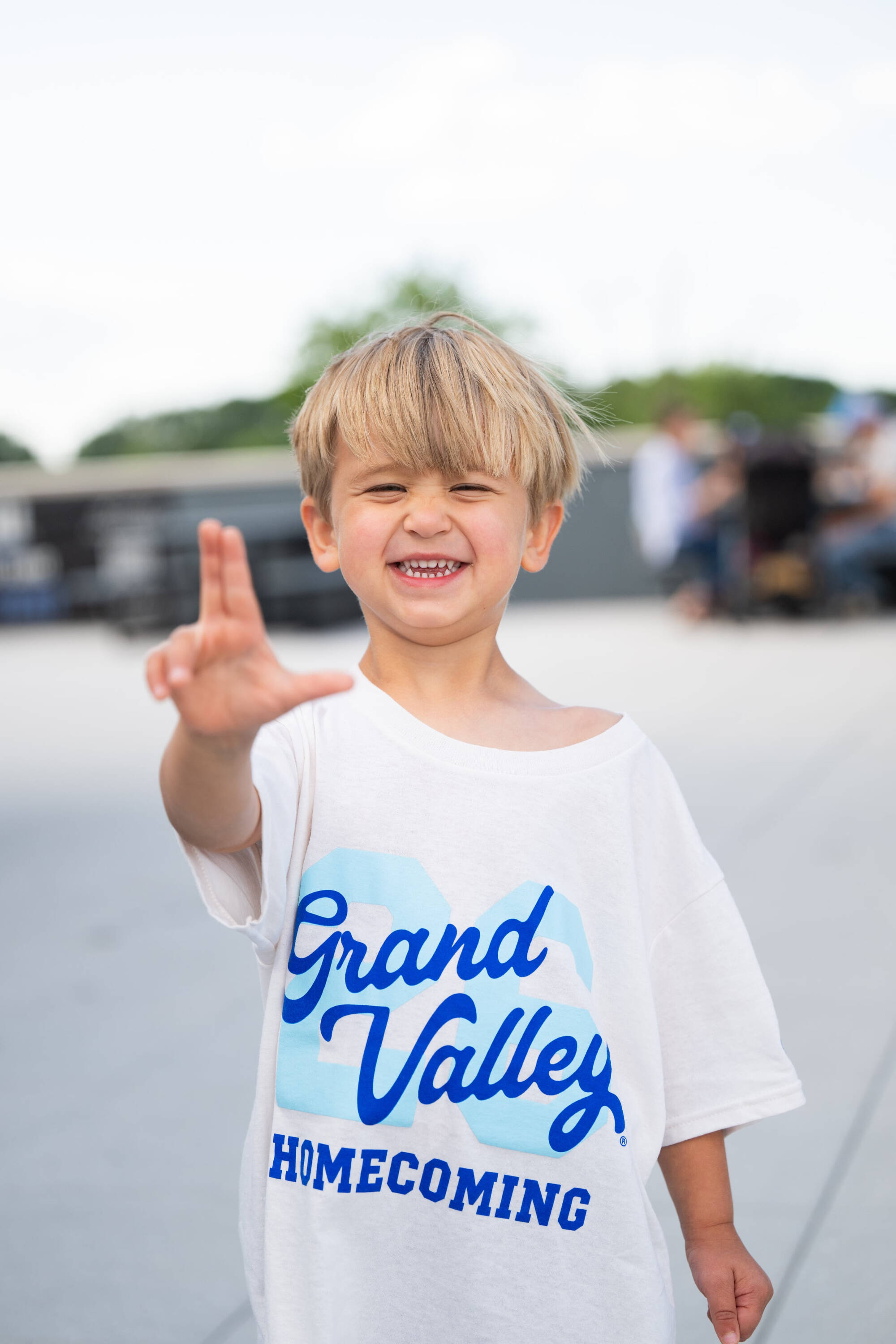 Little Laker smiles doing anchor up sign wearing GVSU Homecoming shirt
